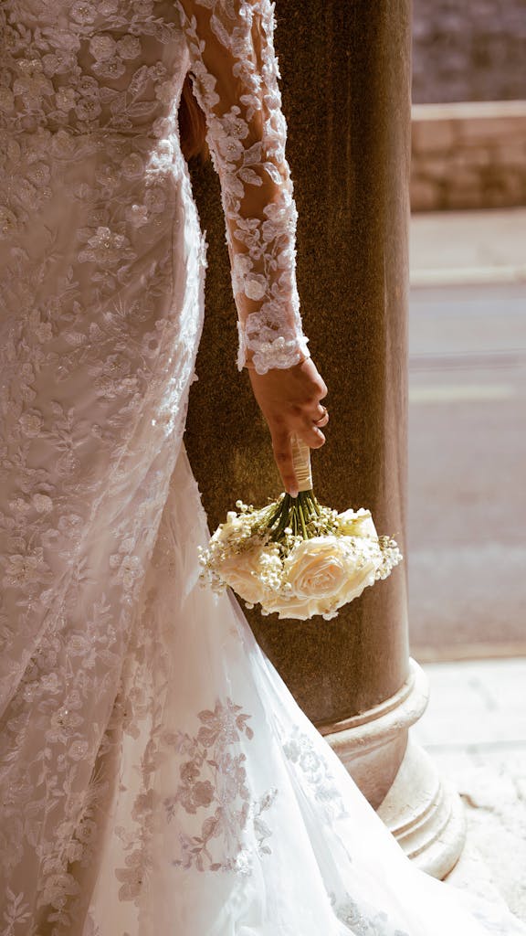 Détail de la mariée de dos tenant son bouquet : une image d'une grande douceur photographiée par le Studio Vauban. C'est tout l'art de votre photographe mariage Jeanménil dans chaque cliché.